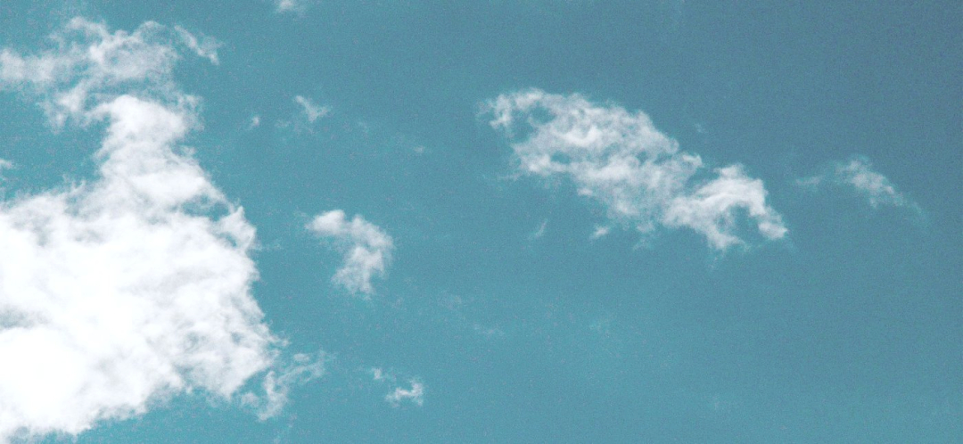 A blue sky with wispy white clouds